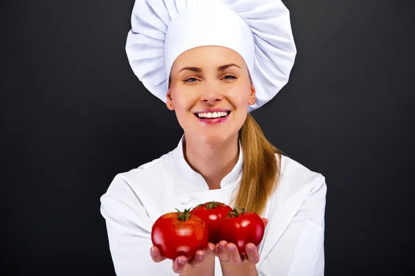 Portret van een jonge vrouw chef-kok met tomaten — Stockfoto