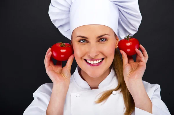 Portret van een jonge vrouw chef-kok met tomaten — Stockfoto