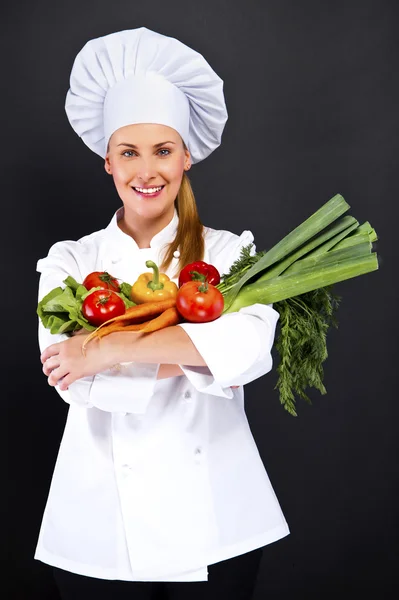 Woman chef make hand heart sign with tomato over dark background — Stock Photo, Image