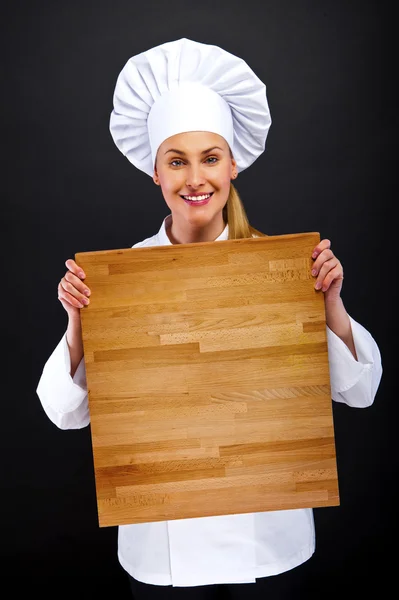 Chef woman on dark background in shock behind wooden board — Stock Photo, Image