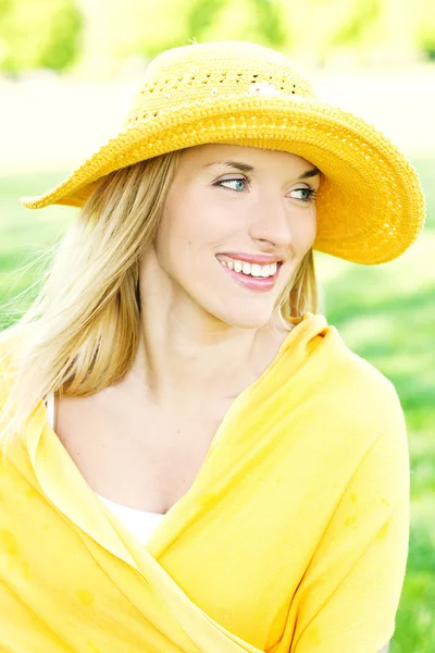 Glimlachende jonge vrouw poseren met een hoed over heldere achtergrond — Stockfoto