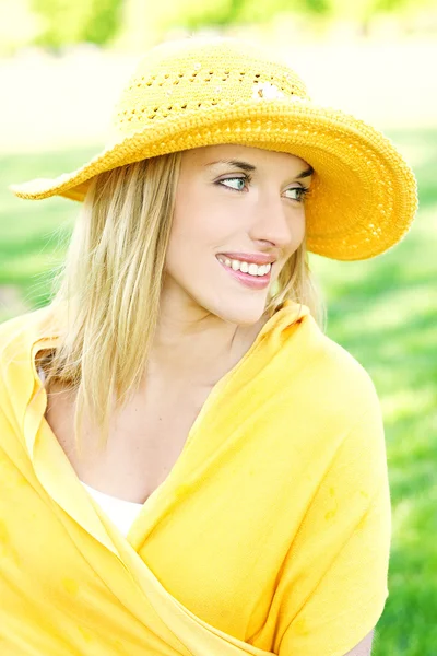 Χαμογελαστή νεαρή γυναίκα που ποζάρει με ένα καπέλο πάνω από φωτεινό φόντο — Φωτογραφία Αρχείου