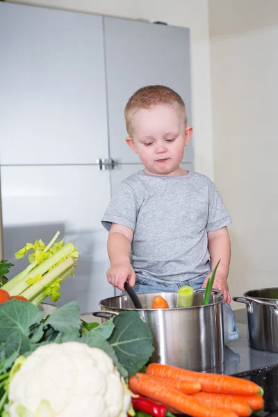 Happy child at kitchen preparing soup — Stock Photo, Image