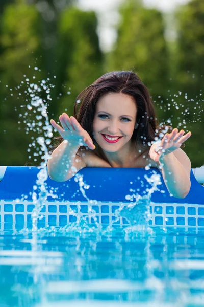 Žena v zahradě, stříkající vodě z bazénu — Stock fotografie