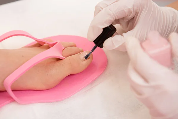 Close-up de um esteticista aplicando verniz nas unhas aos pés da mulher — Fotografia de Stock