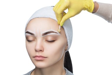 The make-up artist plucks her eyebrows, before the procedure of permanent make-up in the beauty salon.