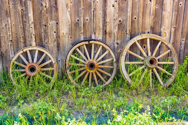 Trzy Stare Wietrzne Drewniane Koła Wagonu Pod Ścianą Stodoły — Zdjęcie stockowe
