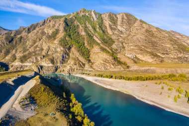 Mavi nehir yukarıdan dronlar tarafından alınan dağların arasından akar.
