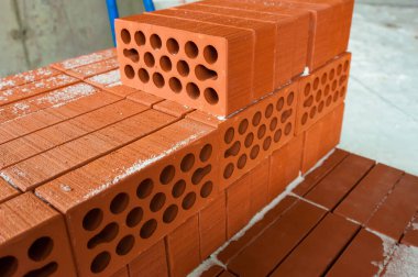 Kırmızı tuğla inşaat alanındaki paletlerde yatıyor.