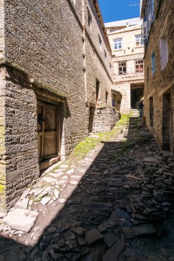 Terk edilmiş eski evler. Taş duvarlar arasında dar bir sokak.