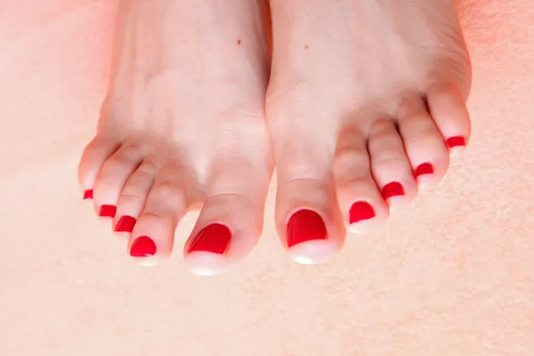 Pies de mujer con uñas rojas en la toalla —  Fotos de Stock
