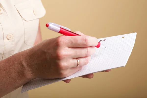 Cuaderno de notas y una pluma roja en las manos de las mujeres —  Fotos de Stock