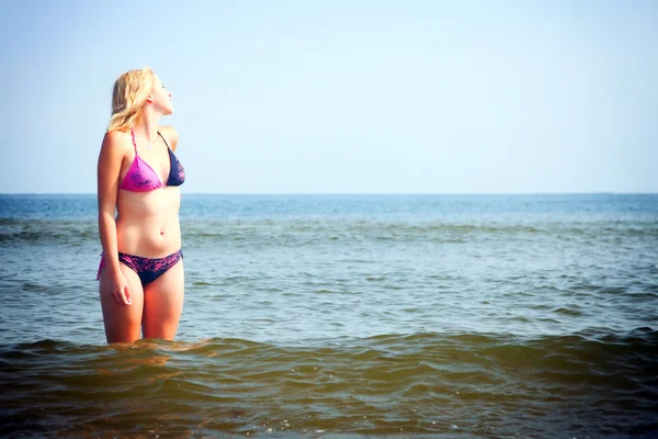 Hermosa mujer en bikini tomando el sol junto al mar — Foto de Stock