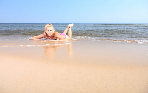 Hermosa mujer en bikini tomando el sol junto al mar — Foto de Stock