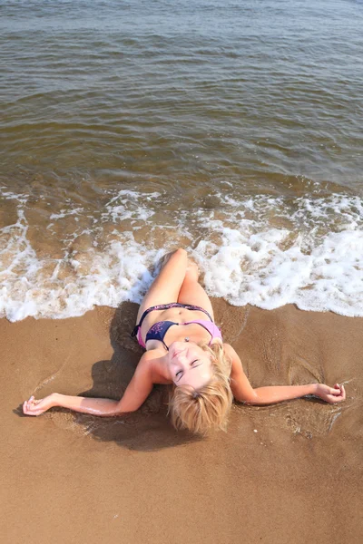 Hermosa mujer en bikini tomando el sol junto al mar — Foto de Stock