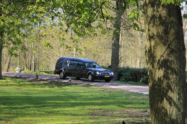 Schwarzer Leichenwagen auf Friedhof — Stockfoto