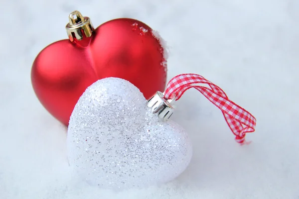 Ornements coeur rouge et blanc dans la neige — Photo