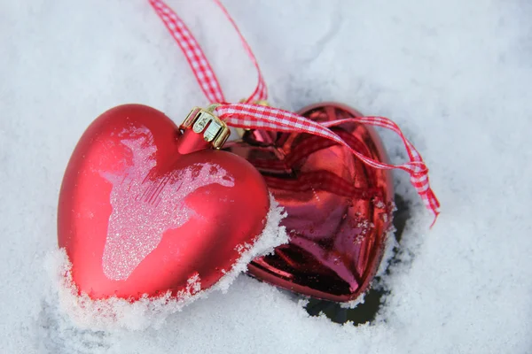 Red and white heart ornaments in snow — Stock Photo, Image