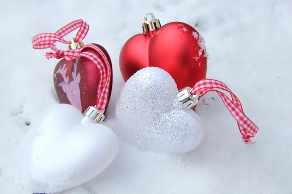 Red and white heart ornaments in snow — Stock Photo, Image