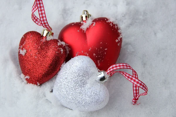 Enfeites de coração vermelho e branco na neve — Fotografia de Stock