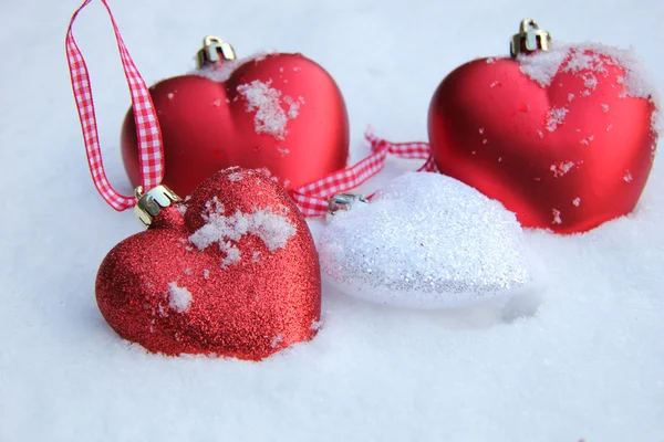 Red and white heart ornaments in snow — Stock Photo, Image