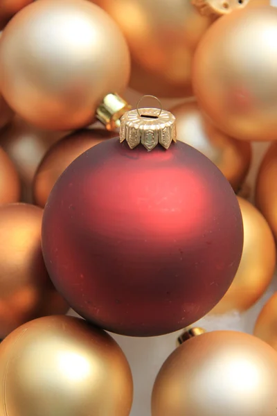 Red ornament on a pile of golden ornaments — Stock Photo, Image