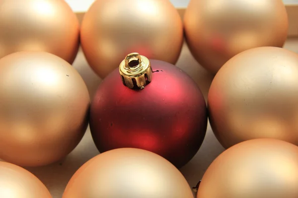 Rotes Ornament auf einem Haufen goldener Ornamente — Stockfoto