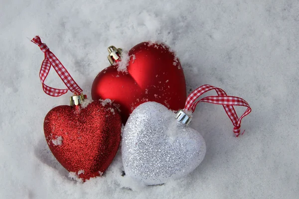 Adornos rojos y blancos del corazón en la nieve — Foto de Stock