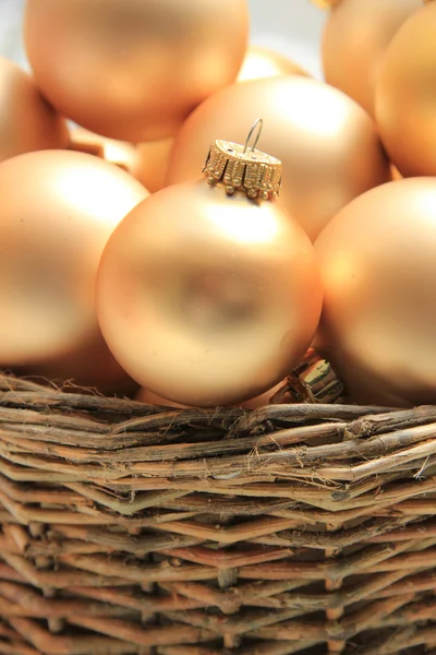 Adornos de Navidad dorados en una canasta de mimbre —  Fotos de Stock