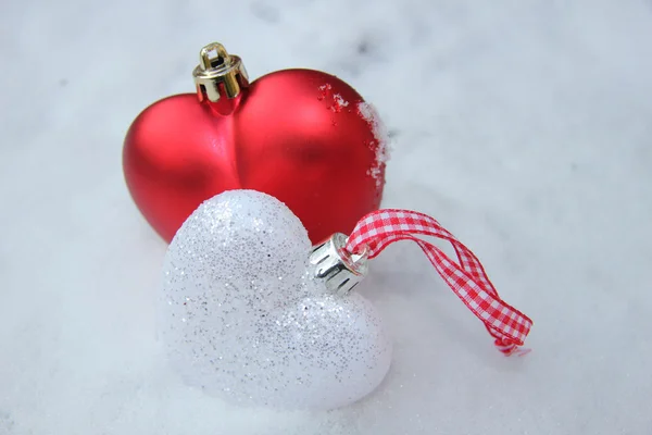 Червоно-білі серцеві прикраси в снігу — стокове фото