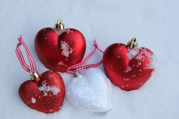 Ornamenti di cuore rossi e bianchi in neve — Foto Stock
