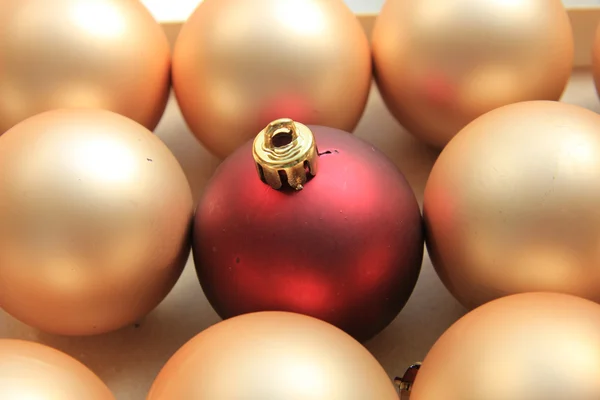 Rotes Ornament auf einem Haufen goldener Ornamente — Stockfoto