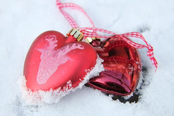 Red and white heart ornaments in snow Royalty Free Stock Photos