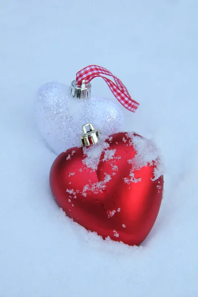 Adornos rojos y blancos del corazón en la nieve — Foto de Stock