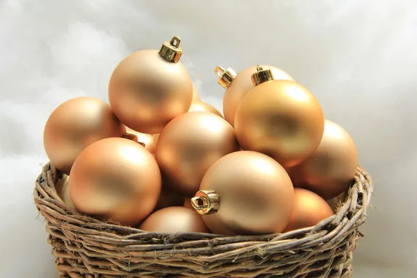 Adornos de Navidad dorados en una canasta de mimbre —  Fotos de Stock