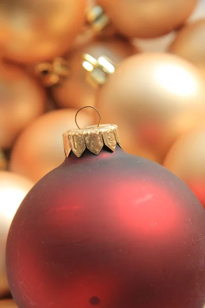 Rotes Ornament auf einem Haufen goldener Ornamente — Stockfoto