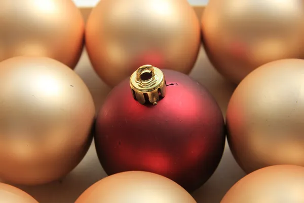 Ornamento vermelho em uma pilha de ornamentos dourados — Fotografia de Stock