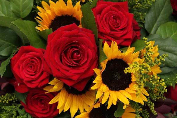 Rode rozen en zonnebloemen in een floral arrangement — Stockfoto