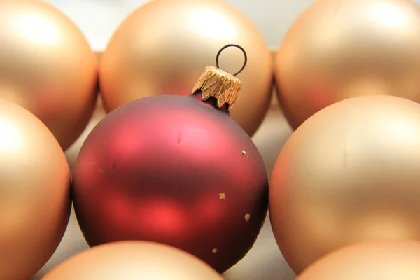 Ornamento rosso su un mucchio di ornamenti d'oro — Foto Stock