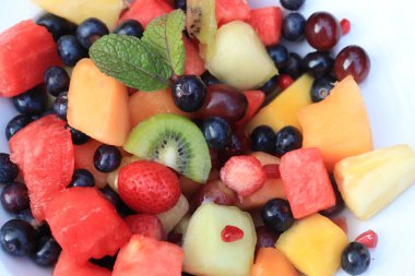 Parlak renklerde taze meyve salatası, taze nane yapraklarıyla süslenmiş.