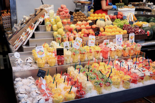 Barcelona, Spain - sSeptember 30th 2019: Colorful fruit and fruit salads in plastic containers at La Boqueria Market. Различные виды фруктового салата в пластиковых контейнерах