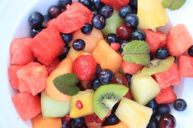 Parlak renklerde taze meyve salatası, taze nane yapraklarıyla süslenmiş.