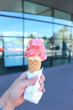 Pembe yumuşak buzlu waffle külahı tutan bir kadın.