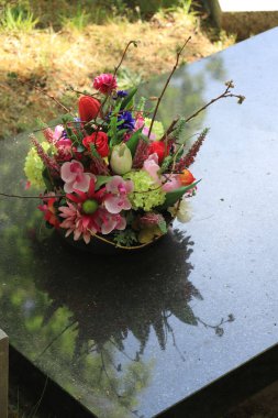 Gri mermer bir mezarda çok renkli cenaze çiçekleri