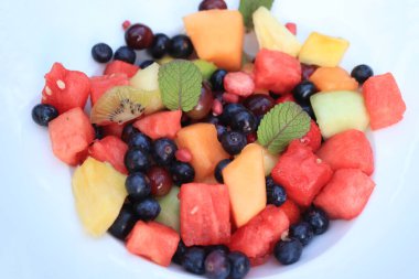 Parlak renklerde taze meyve salatası, taze nane yapraklarıyla süslenmiş.