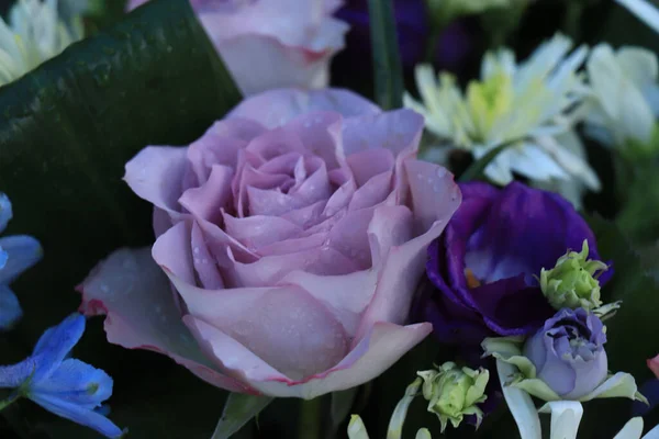Purple and blue flower arrangement for a wedding: purple roses and blue larkspur
