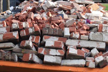 Old, demolished bricks in an orange garbage dumpster