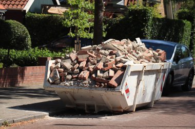 Çöp bidonu inşaat alanının yakınındaki eski tuğlalarla dolu.