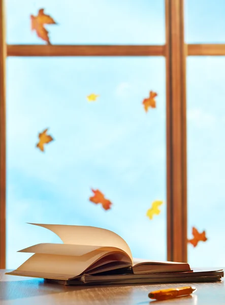 Schoolboeken op venster achtergrond met esdoorn bladeren — Stockfoto