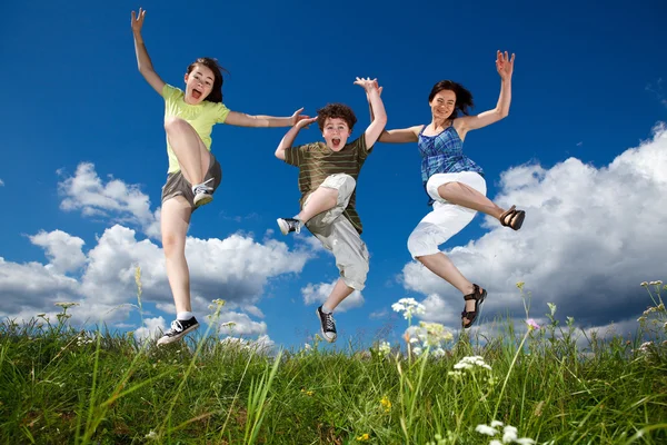 Активна сім'я - мати і діти бігають, стрибають на відкритому повітрі — стокове фото